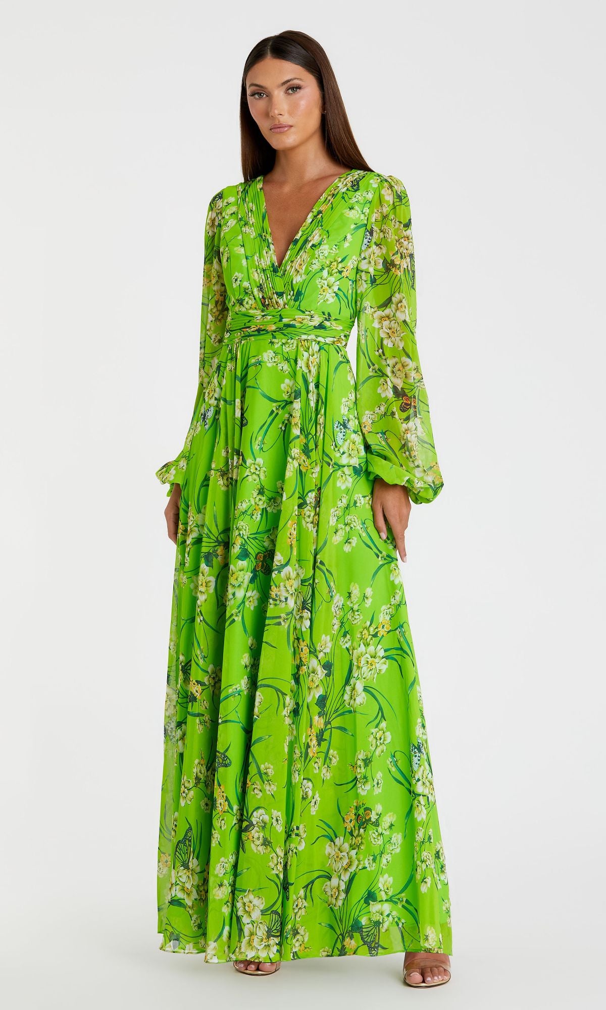 A woman models the Mac Duggal 56013 Long Green Print Formal Dress featuring long sleeves, a V-neckline, and bright floral print—standing out elegantly against a plain white background.